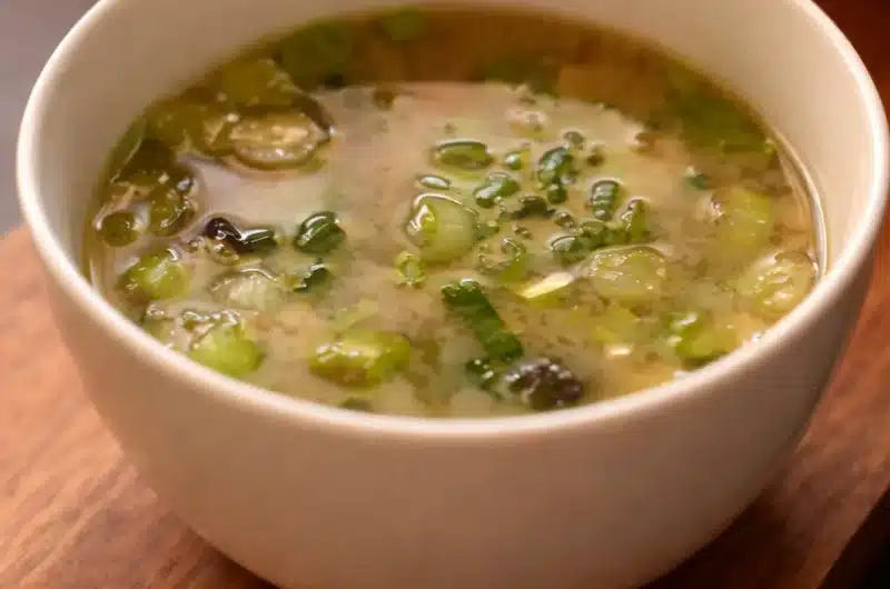 Bowl of Miso Soup with Tofu and Scallions garnished with greens.